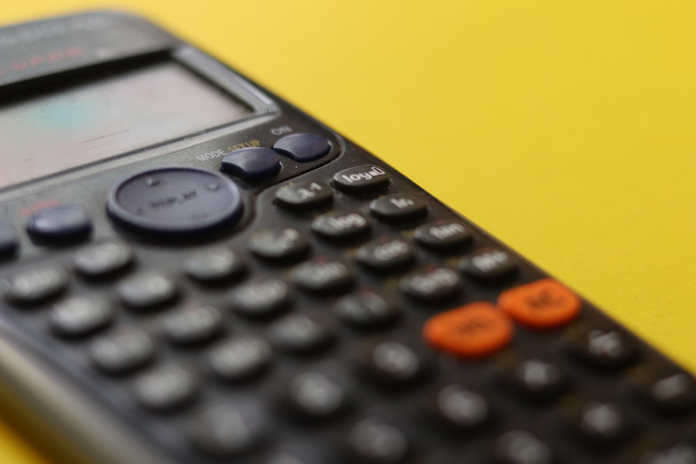 A black calculator against a yellow surface